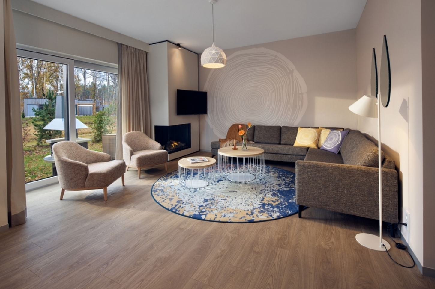 De leefruimte van een cottage van Terhills Resort by Center Parcs, met zetels, televisie en haardvuur.